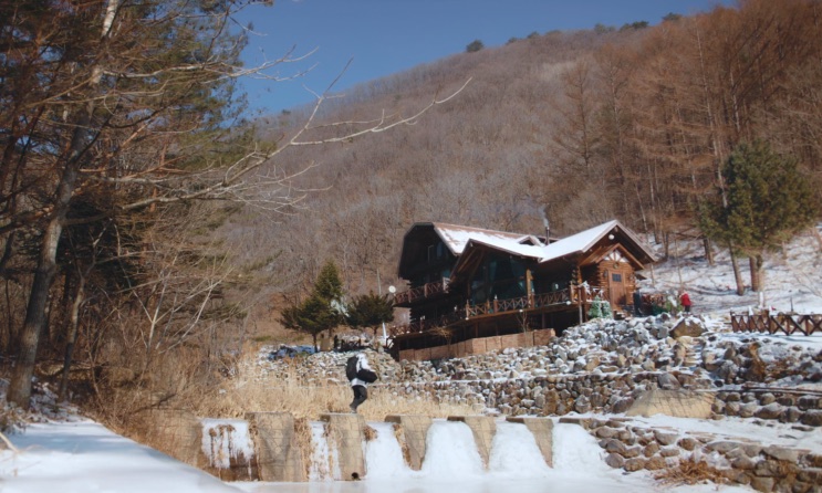A cabana vista de longe, no fundo de um vale de montanha no inverno