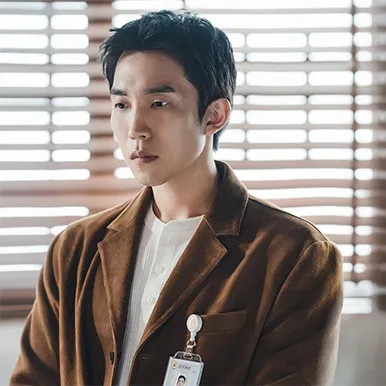 Lee Dong-jin de paletó marrom, com o crachá da polícia no bolso