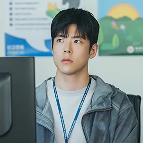 Beom Seong-hun de jaqueta clara, sentado diante do computador