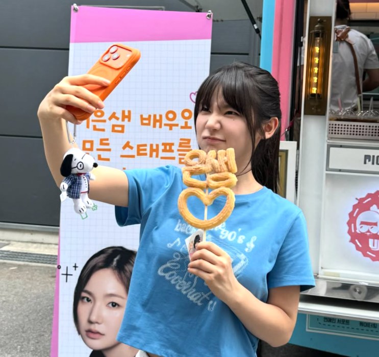 Lee Eun-saem tirando uma selfie ao lado de um food truck de fãs