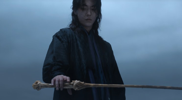 O Gu-cheon segurando a arma, uma haste que parece feita de osso
