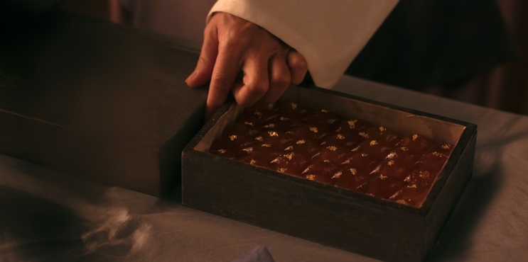 Mão abrindo a caixa com os doces cobertos de folha de ouro