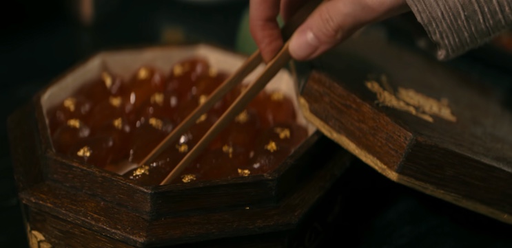 Caixa octogonal cheia de doces com folha de ouro, com hashi por cima