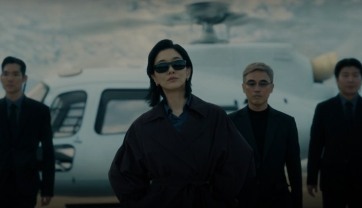 Kusanagi Jin de óculos escuros, descendo de um helicóptero com seguranças atrás