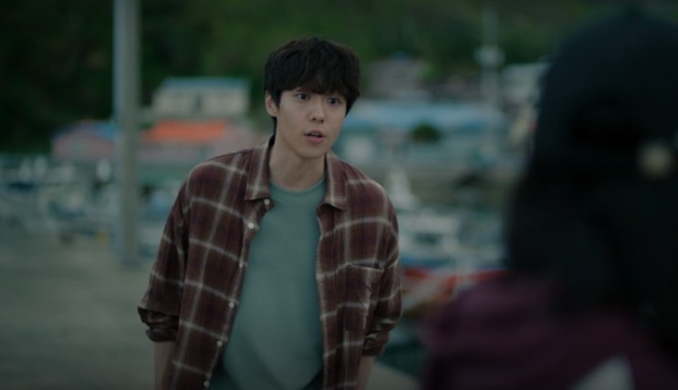 Kim Woo-jin de camisa xadrez, no porto da ilha