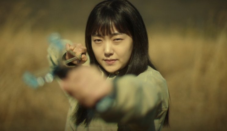 Ji-an apontando uma arma num campo aberto em A Shop for Killers
