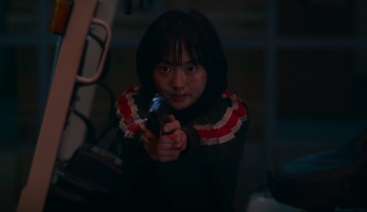 Ji-an agachada, apontando uma arma, em A Shop for Killers