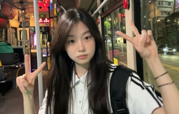 Seo Su-min fazendo sinal de paz dentro de um ônibus