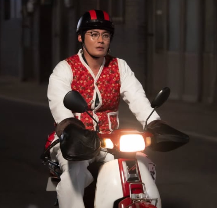 Sung Han-soo de capacete, andando de moto à noite