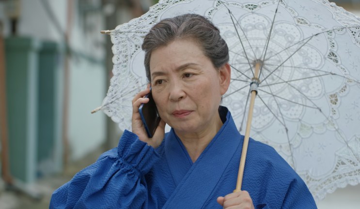 A Paeng Myo-sun ao telefone segurando uma sombrinha de renda