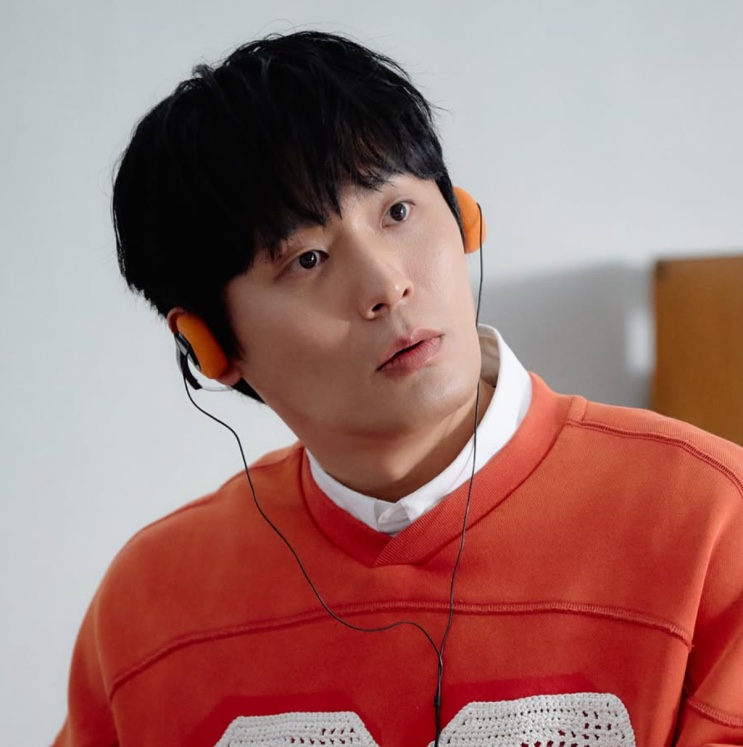 Choi Dae-hoon em cena, de moletom laranja