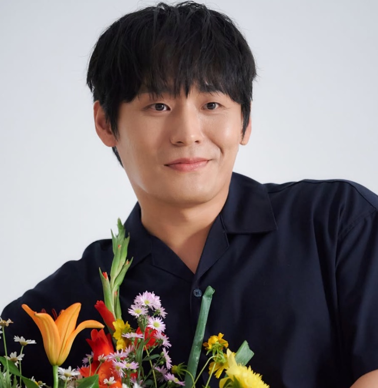 Choi Dae-hoon sorrindo com um buquê de flores