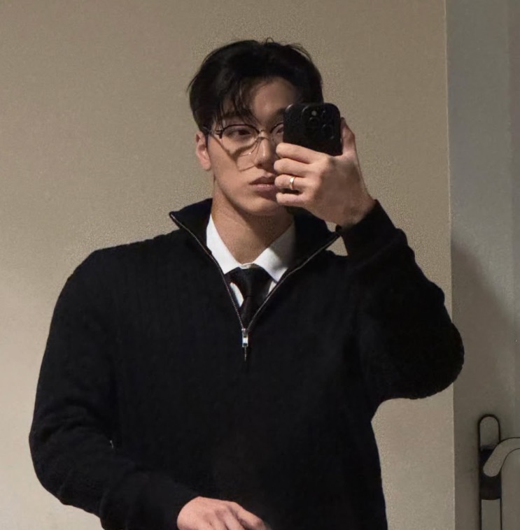 Selfie de Choi San no espelho, de suéter preto de gola e óculos