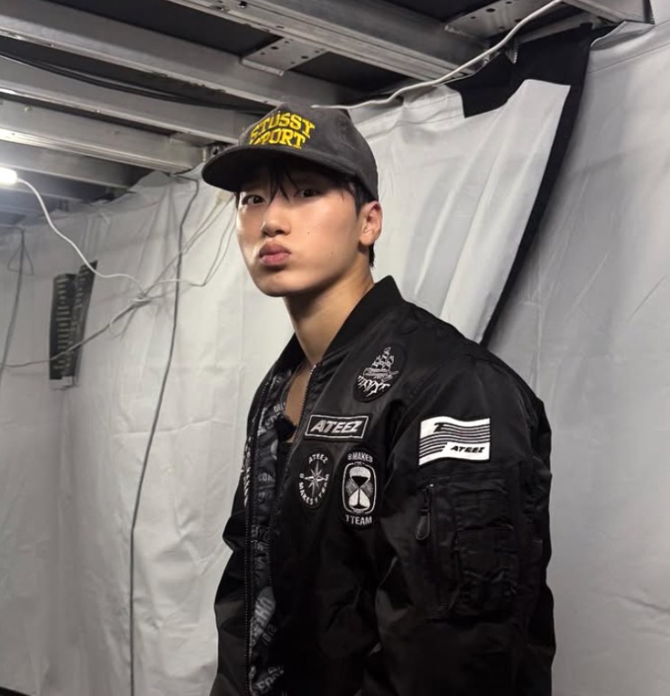 Choi San de boné e jaqueta bomber do ATEEZ, nos bastidores