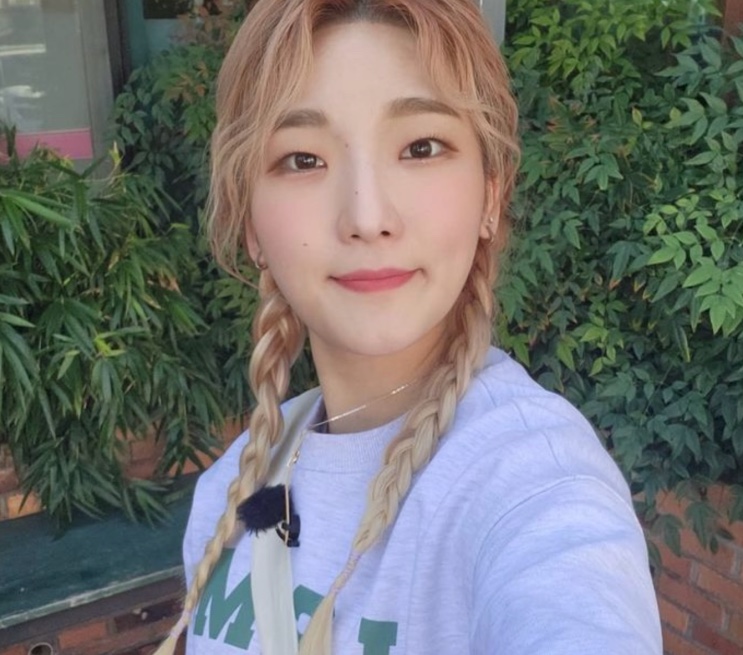 Heebab, a youtuber de mukbang, numa selfie sorrindo, de cabelo loiro trançado