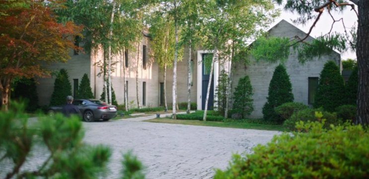 Fachada de pedra da casa, com um carro estacionado no pátio de paralelepípedos