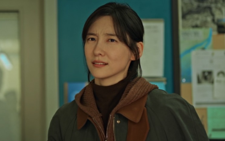 Lee Kang-hyun de pé na delegacia, com expressão séria