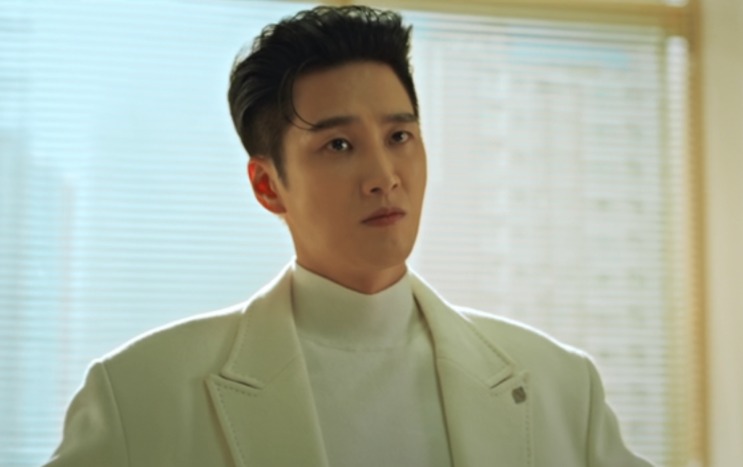 Jin Yi-soo de casaco branco, num corredor claro