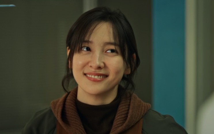 Lee Kang-hyun sorrindo, de casaco verde
