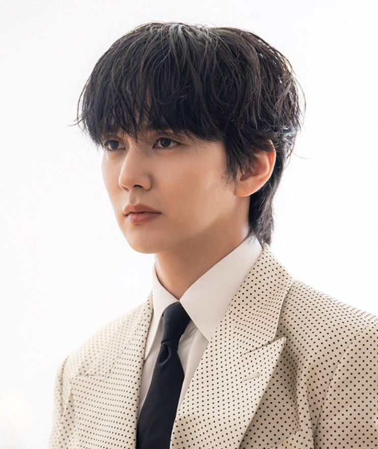 Yoo Seong-won de terno claro de poás, com o cabelo despenteado