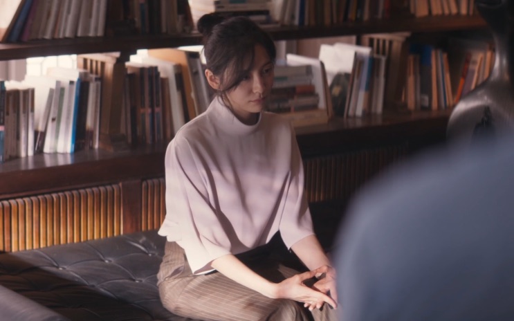 Cho Yeo-jeong sentada num sofá diante de uma estante cheia de livros