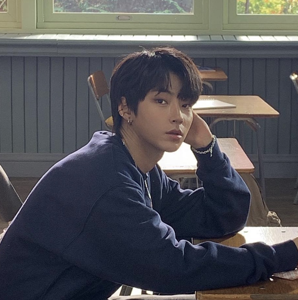 Hwang In-youp sentado numa carteira de escola