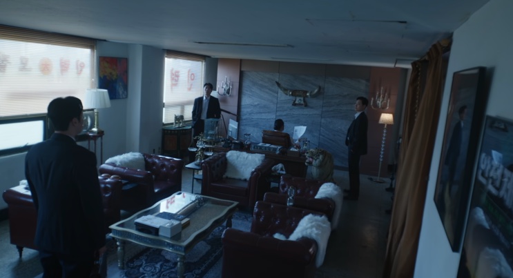 A sala da agência Baekho por dentro, com sofás de couro e homens de terno espalhados pelo ambiente