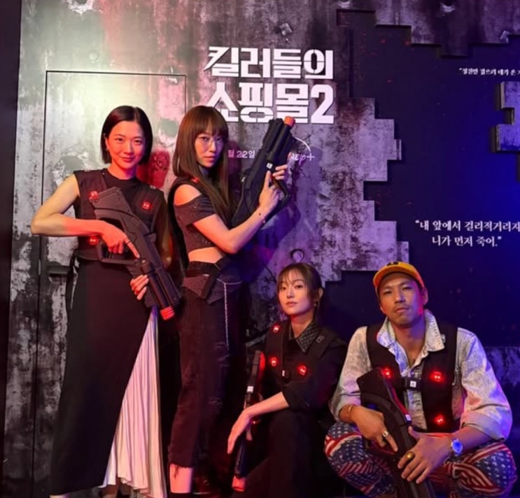 Quatro atores de Uma Loja para Assassinos posando com armas de brinquedo num evento da 2ª temporada
