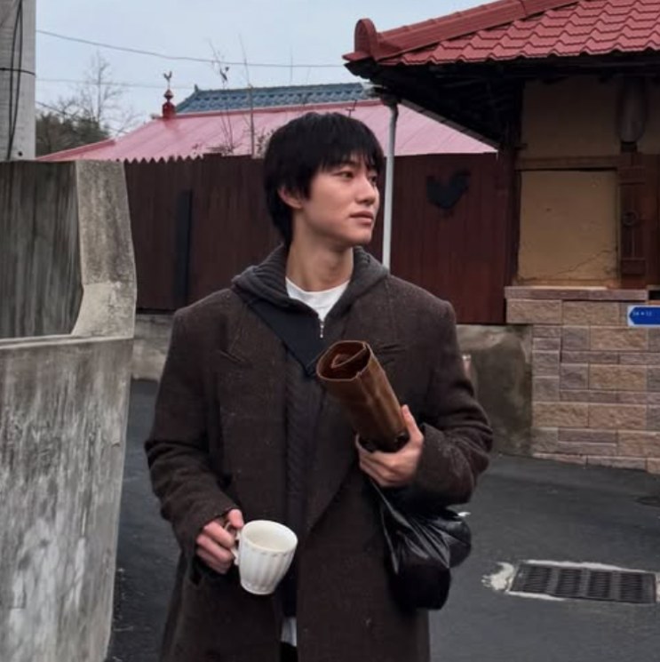 Kwak Dong-yeon caminhando com um café, nos bastidores