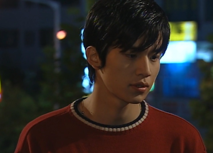 Lee Dong-wook jovem, de suéter vermelho, numa rua à noite