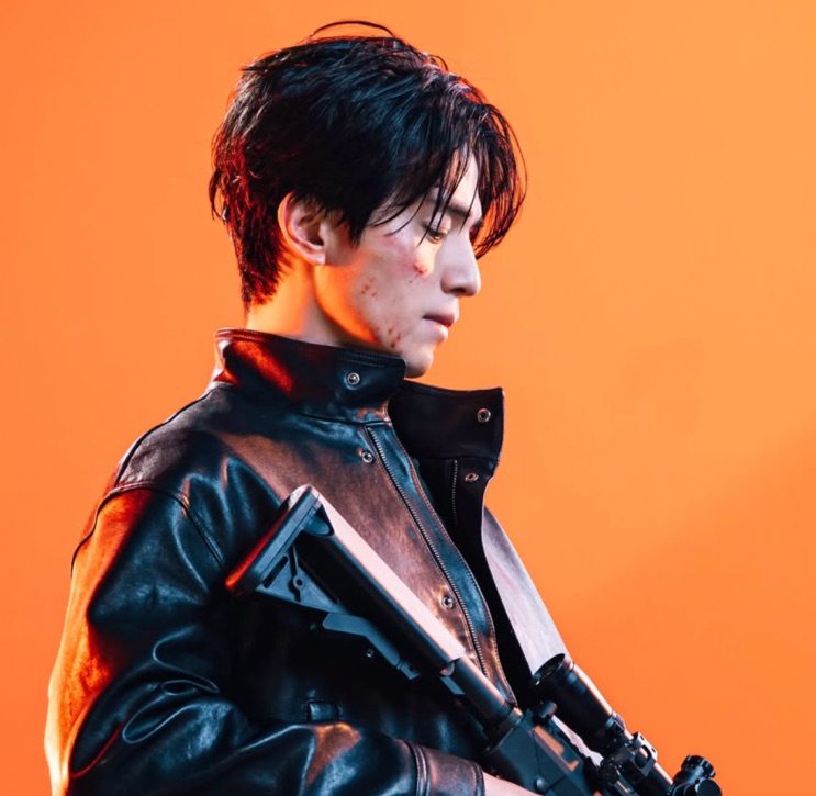 Lee Dong-wook de jaqueta de couro e arma, em imagem de divulgação de fundo laranja