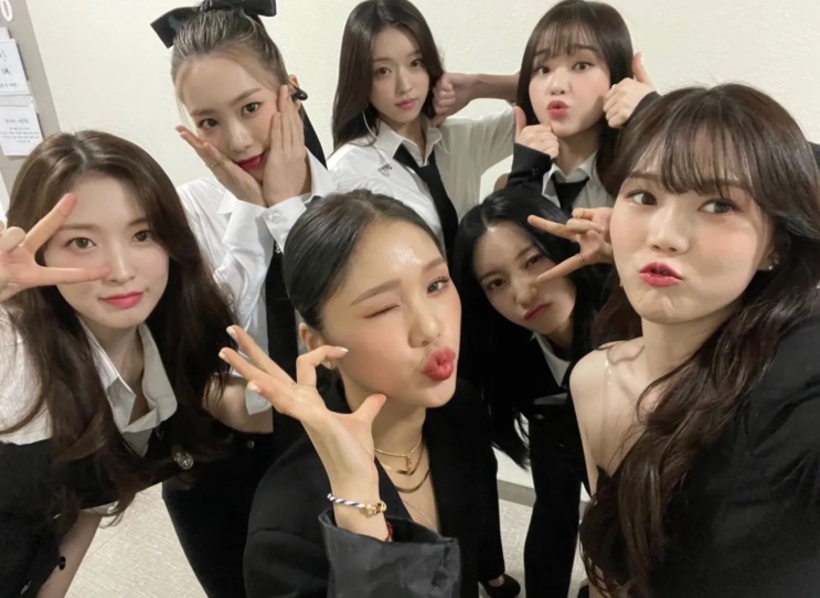 Selfie do OH MY GIRL com as integrantes reunidas, todas de preto e branco