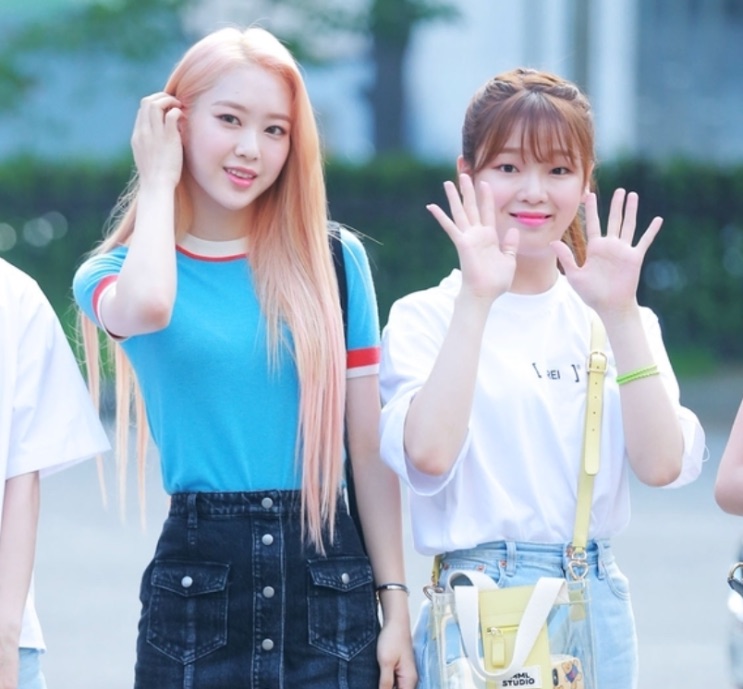 Duas integrantes do OH MY GIRL acenando na rua, em roupa de verão