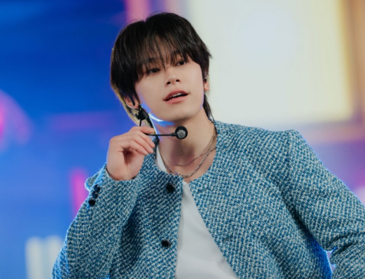O idol Lee Chan no palco, com ponto de ouvido, durante uma apresentação
