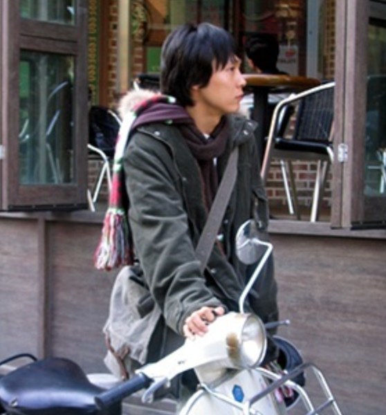 Park Byung-eun jovem, na rua ao lado de uma lambreta