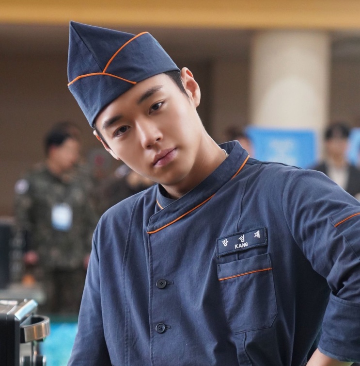 Park Ji-hoon de uniforme e quepe de cozinheiro do quartel, em cena de The Legend of Kitchen Soldier