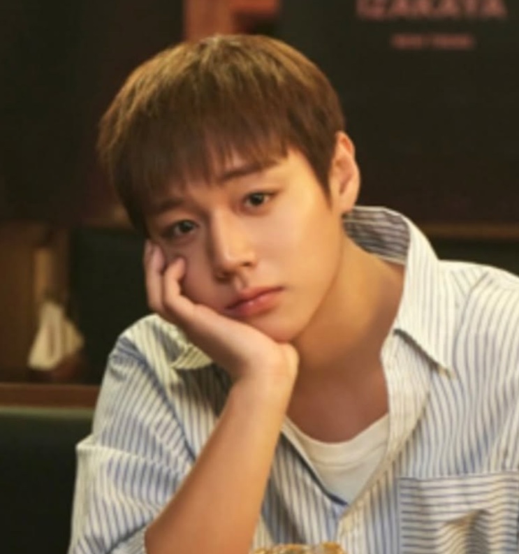 Park Ji-hoon de camisa listrada, com o rosto apoiado na mão