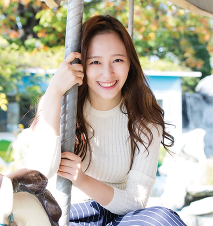Park Ji-hyun sorrindo, sentada num carrossel