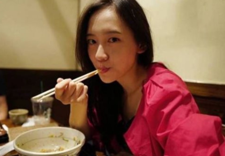 Park Ji-hyun comendo com hashi, olhando para a câmera