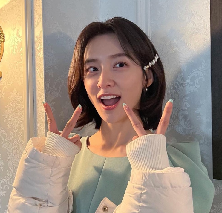 Park Ji-hyun fazendo V com as duas mãos e sorrindo