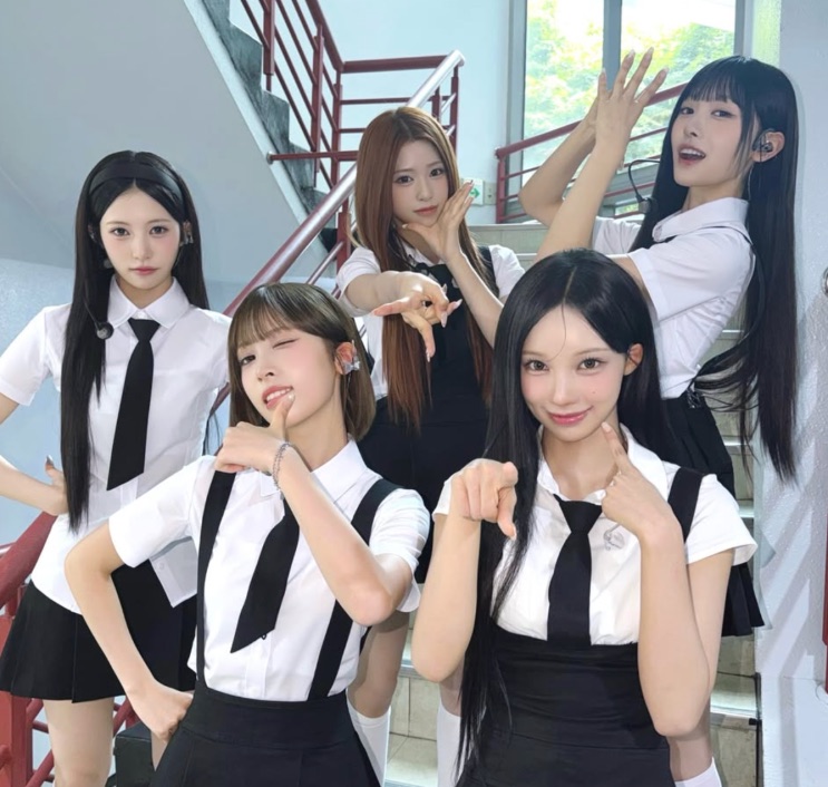 As cinco integrantes do Rescene de uniforme escolar, posando numa escada