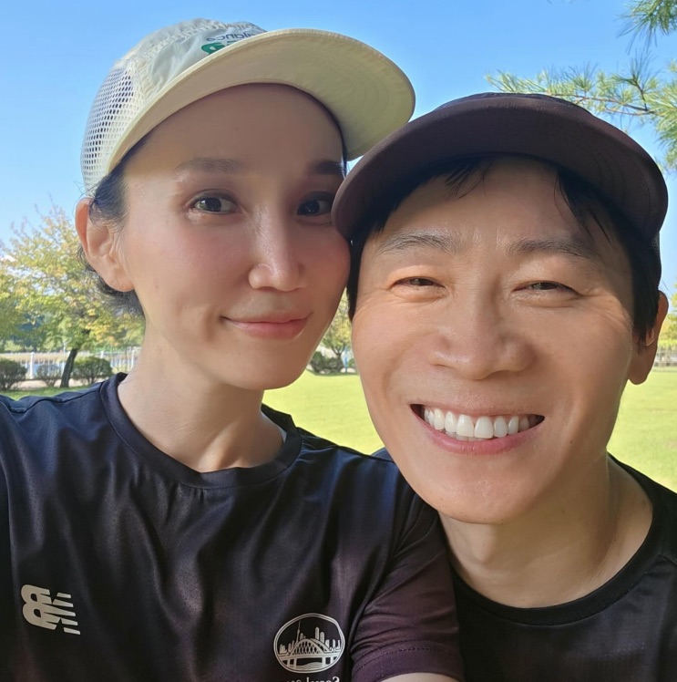Park Bo-kyung e Jin Sun-kyu numa selfie ao ar livre, os dois de boné