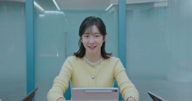 Ji-yoon numa sala de reunião, apresentando com o tablet na mão