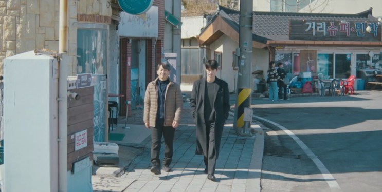 Si-woo e o pai caminhando por uma rua de comércio em Mukho
