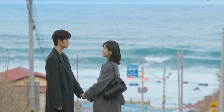Si-woo e Ji-yoon de mãos dadas no cruzamento de Eodal, de frente para o mar