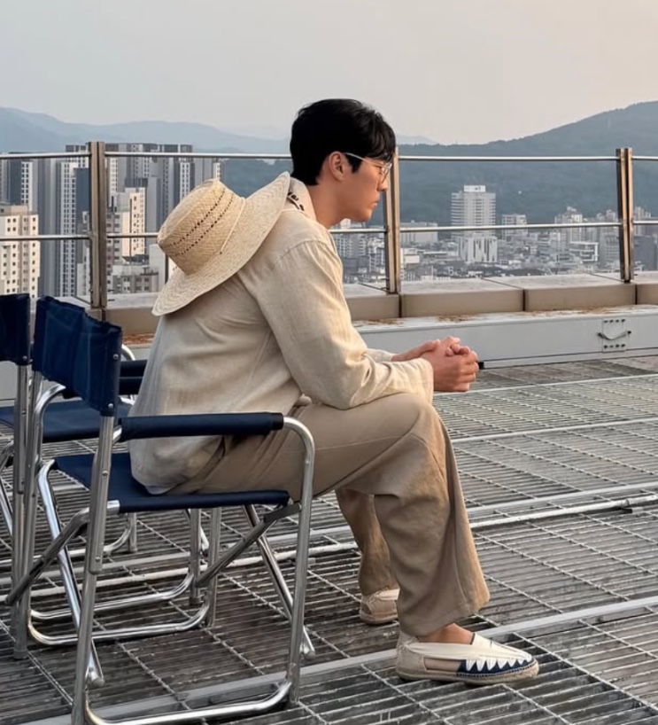 So Ji-sub com chapéu de palha nas costas num terraço
