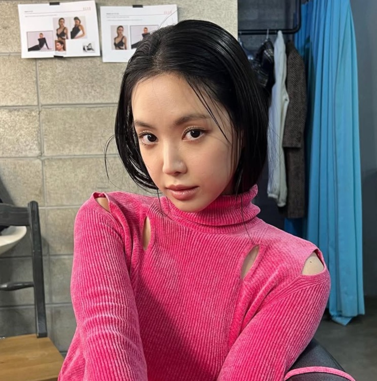 Son Na-eun de suéter rosa, olhando para a câmera