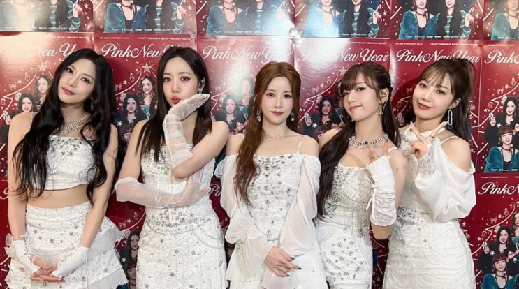Apink em evento, todas de branco, no painel 'Pink New Year'
