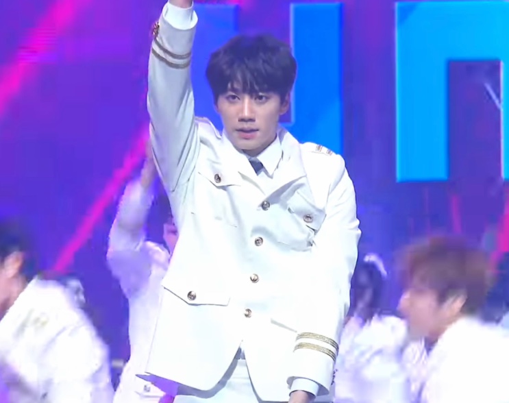 Lee Jun-young erguendo a mão no palco