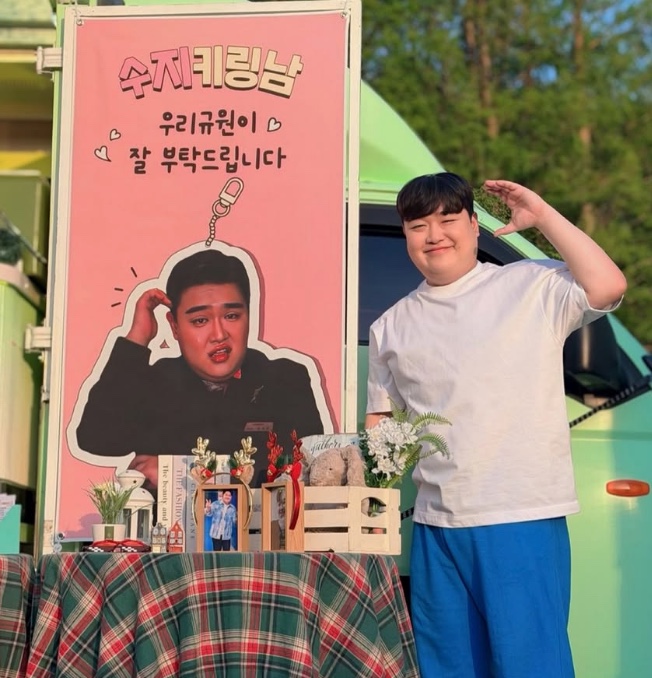 Kim Kyu-won em frente a uma cabine de apoio montada por fãs
